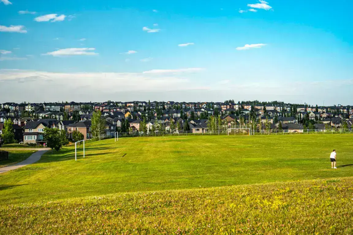 Open playing field with homes and trees beyond in Aspen Woods